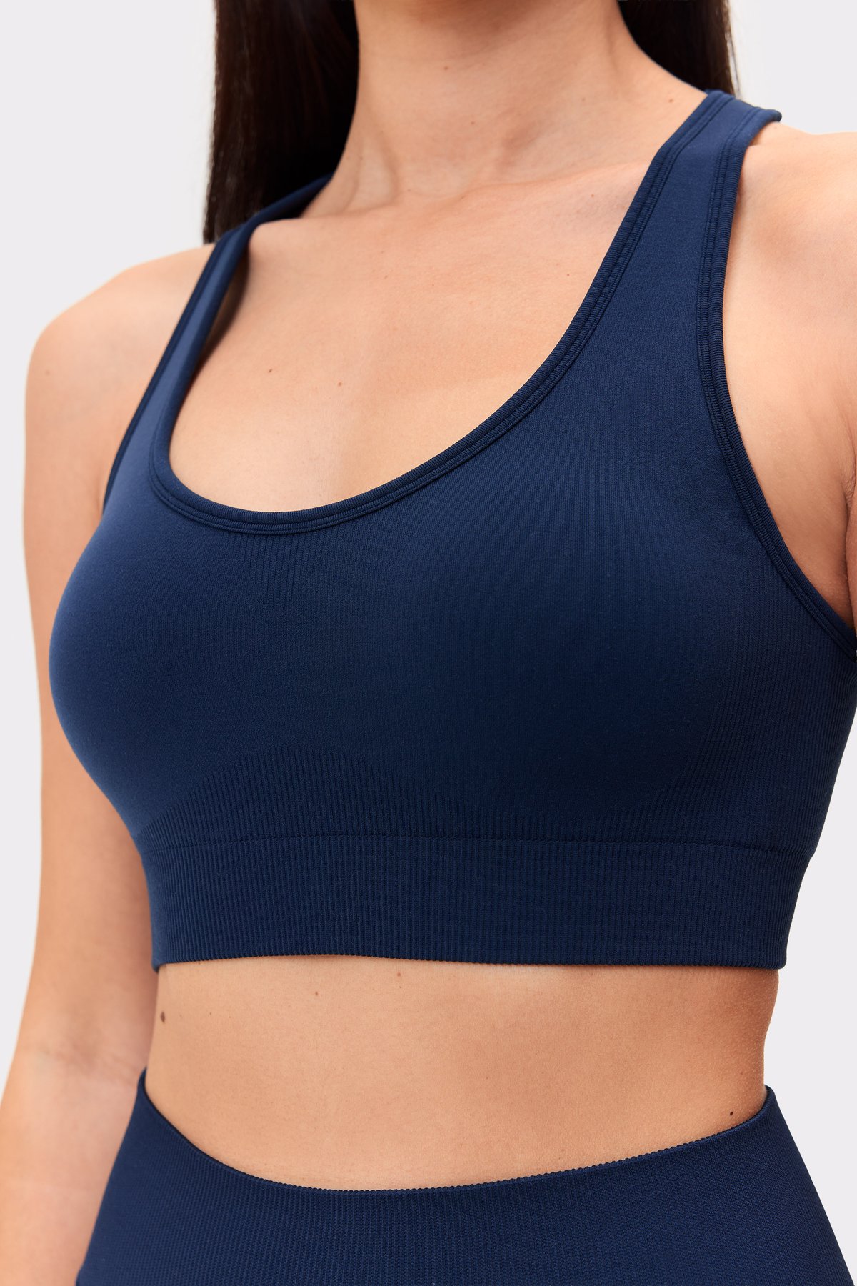 Model trägt den dunkelblauen Seamless Contour Sports Bra von Stronger mit leichtem Halt für Workouts.