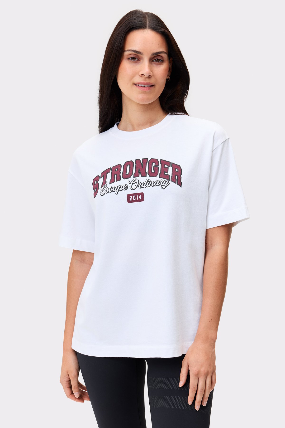 Model in dem hellen weißen Essential T-shirt von Stronger im Regular Fit mit auffälligem Grafikprint auf der Vorderseite.