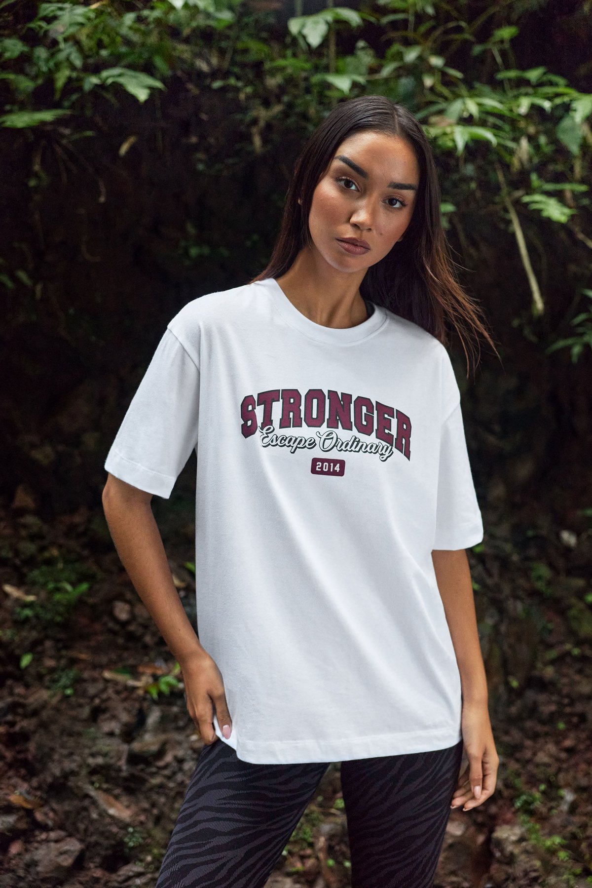 Model trägt das weiße Essential T-Shirt von Stronger mit regulärer Passform und grafischem Print auf der Vorderseite.