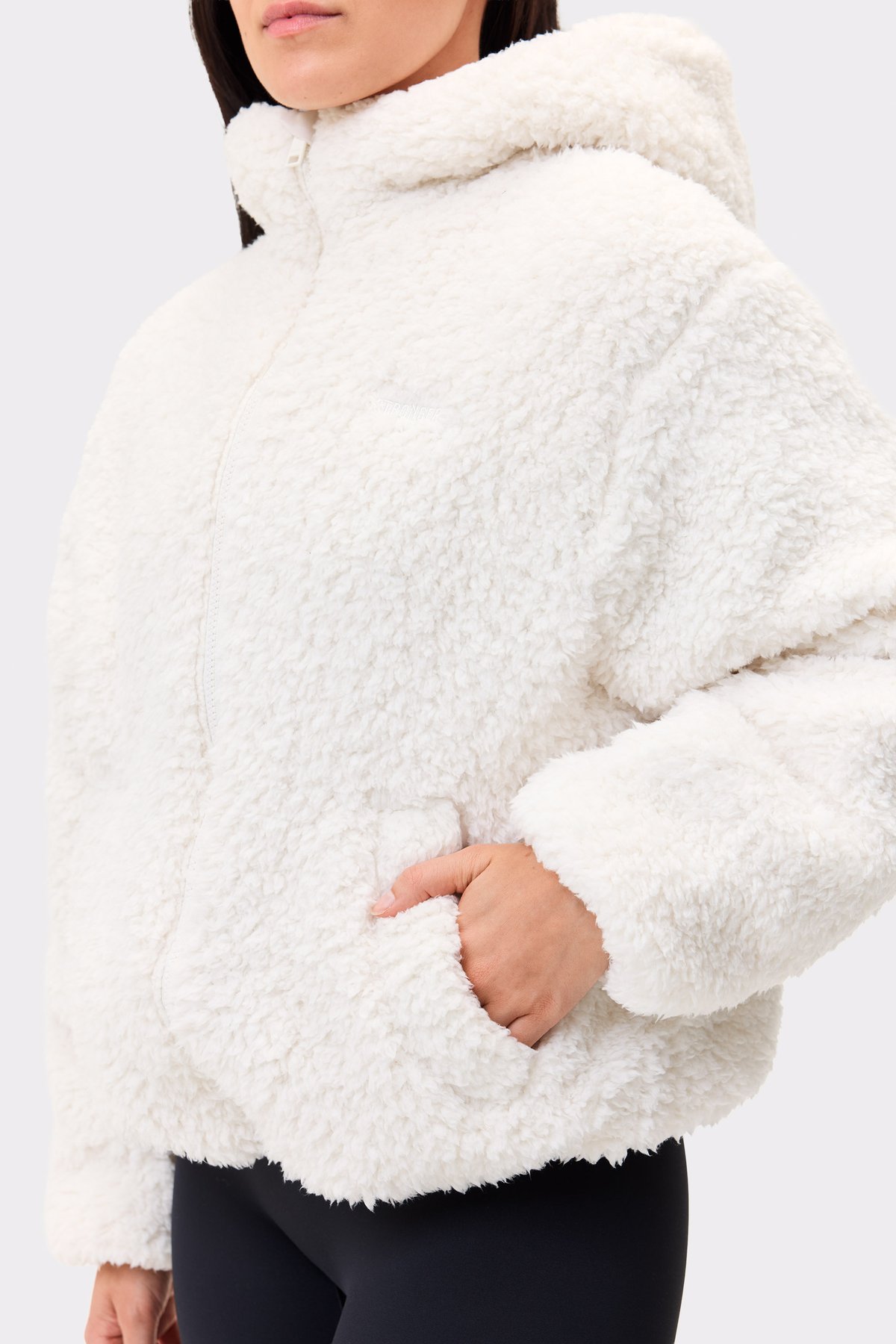 Nahaufnahme der Stronger Hooded Pile Jacket aus recyceltes Polyester, die die weiche Textur und Vordertasche zeigt.