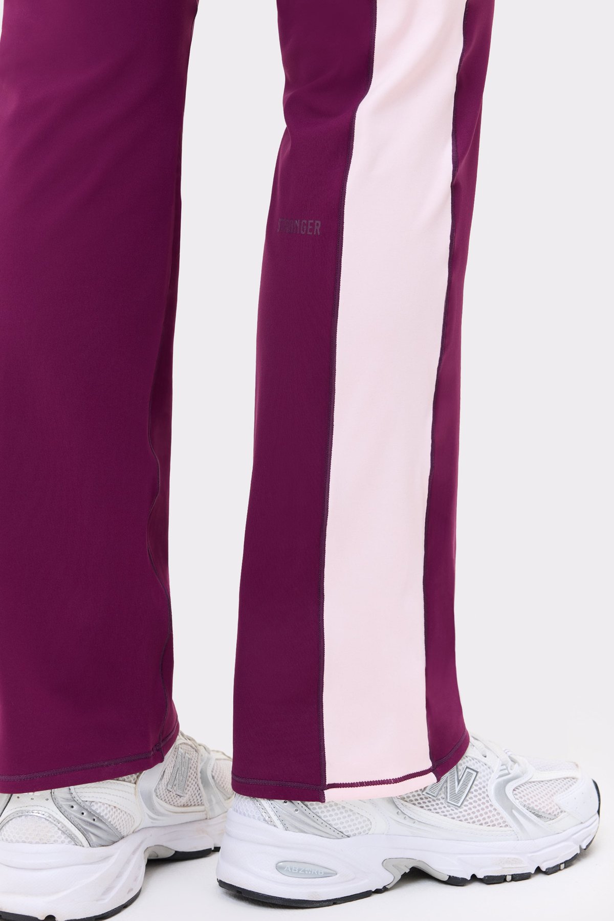 Close-up of the aubergine purple Thermal Bootcut Pants from stronger, showing the light pink side panel and logotype.
