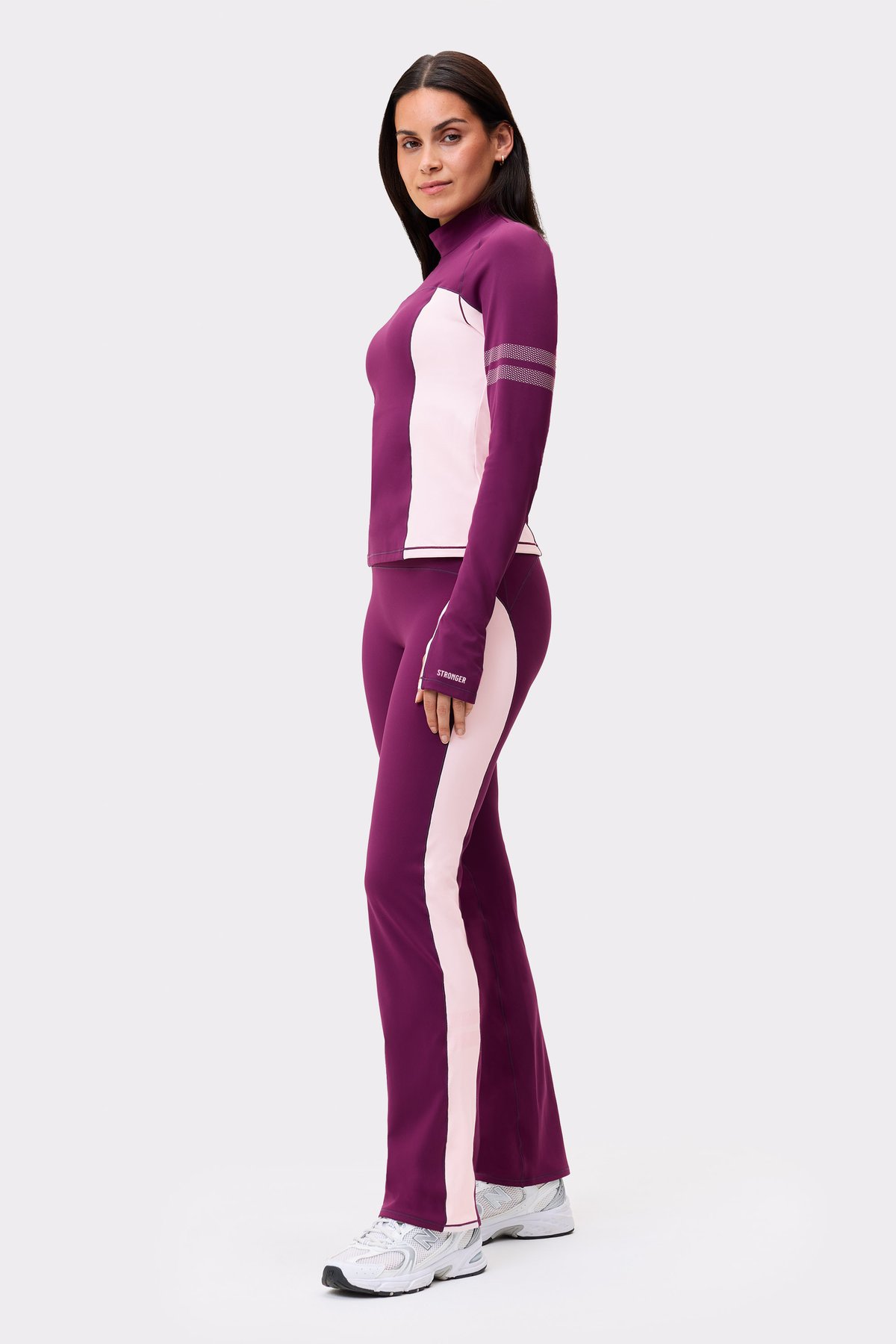 Side view of a model wearing the thermal bootcut pants in aubergine purple and matching top from Stronger.