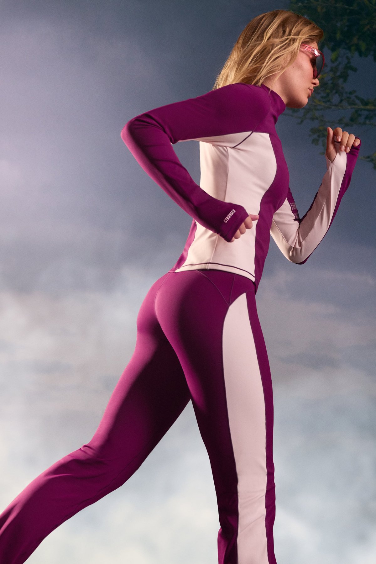 Side view of a woman running outdoors in the aubergine purple thermal bootcut pants and matching top from stronger.