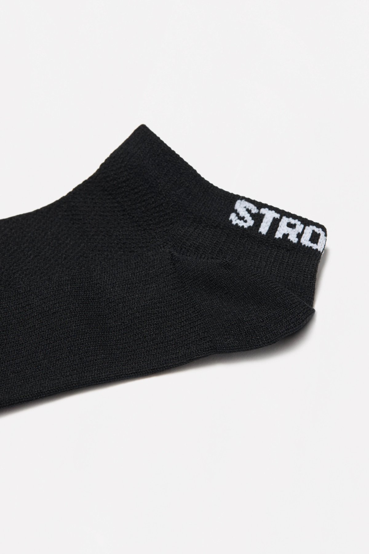 Close-up of the black Sporty Socks from stronger, showing the knitted ankle design and white logotype at the back.