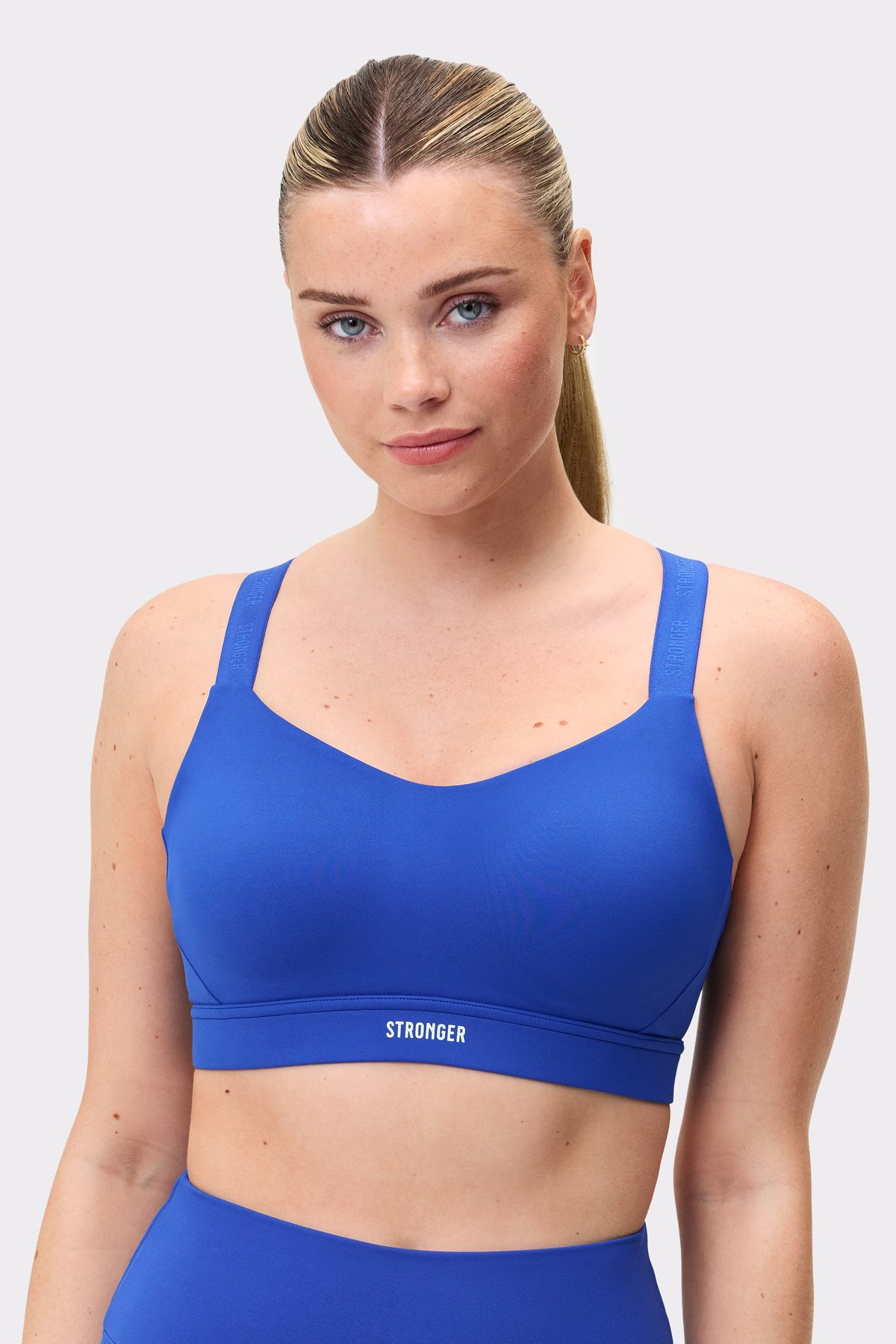 Model trägt den blauen Power Sports Bra von Stronger mit verstellbaren Trägern und starkem Halt für das Training.