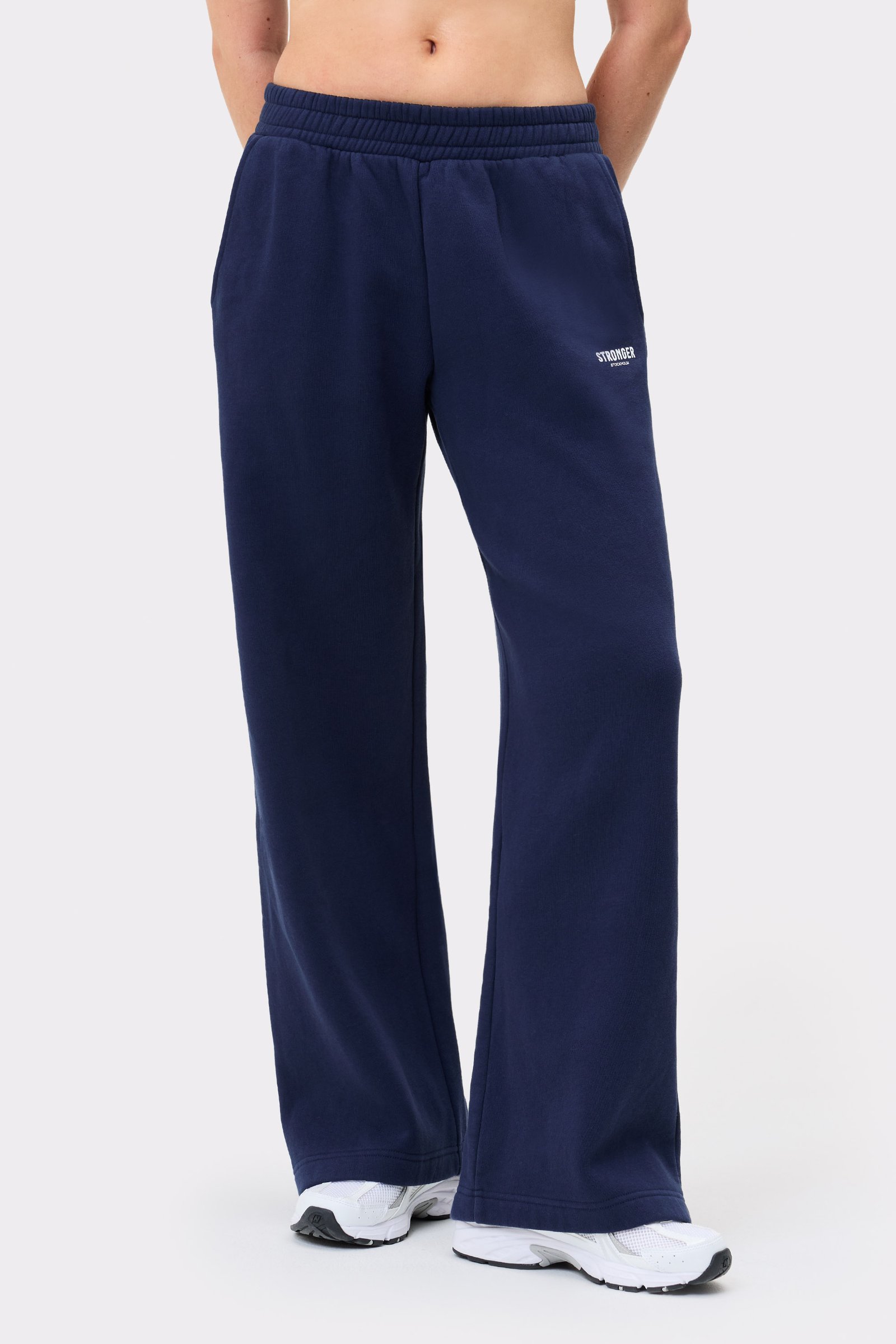 Model trägt dunkelblaue Relaxed Wide Sweatpants von Stronger mit hohem Bund, geradem Bein und Seitentaschen.
