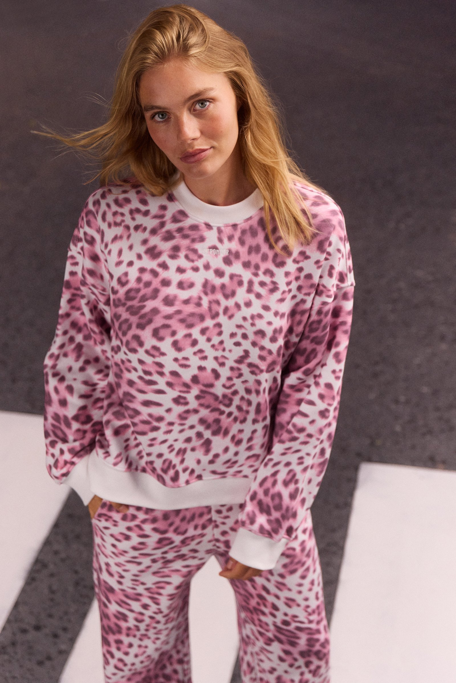 Model wearing the pink leopard print Relaxed Sweatshirt by stronger, featuring a loose fit and ribbed neckline.