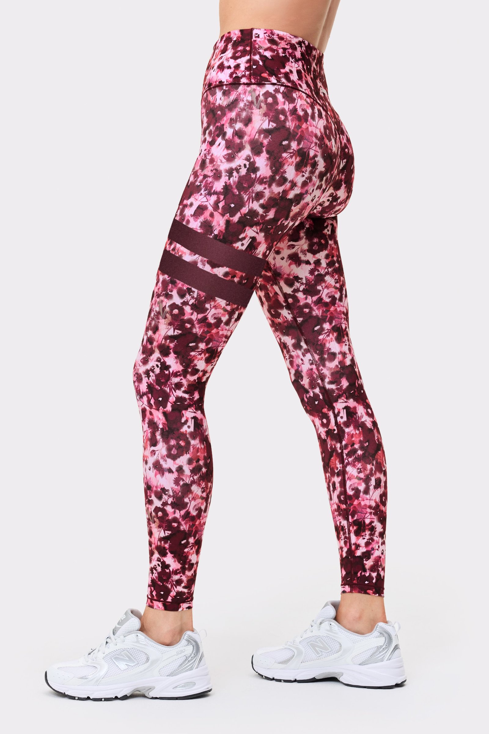 Side view of a model in the Stronger The Signature One Leggings in Autumn Petals, showing the signature lines on the leg.