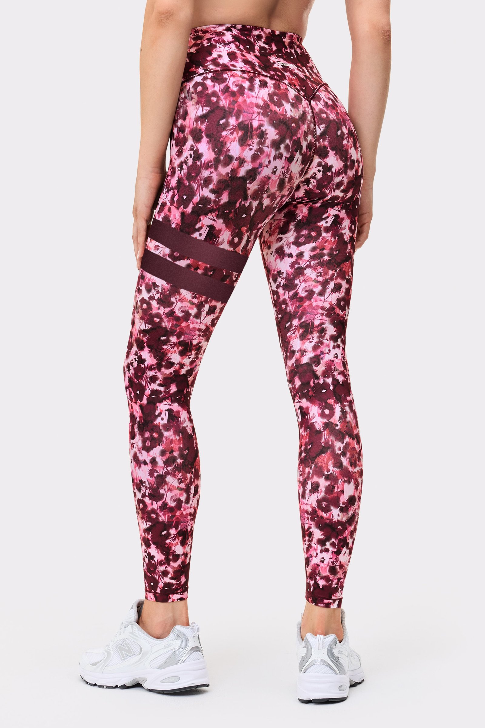 Back view of a woman wearing the Stronger Signature One Leggings in Autumn Petals, showing the signature lines on the leg.