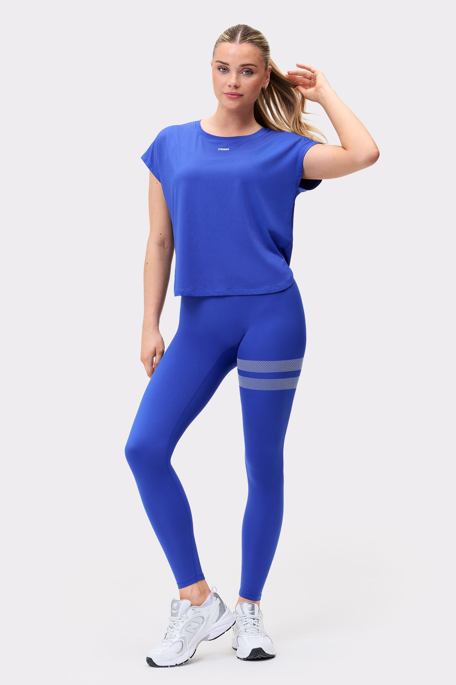 Model in Stronger blauem Drop T-Shirt und passenden Leggings, einem lockeren Funktionsoutfit für Workouts.