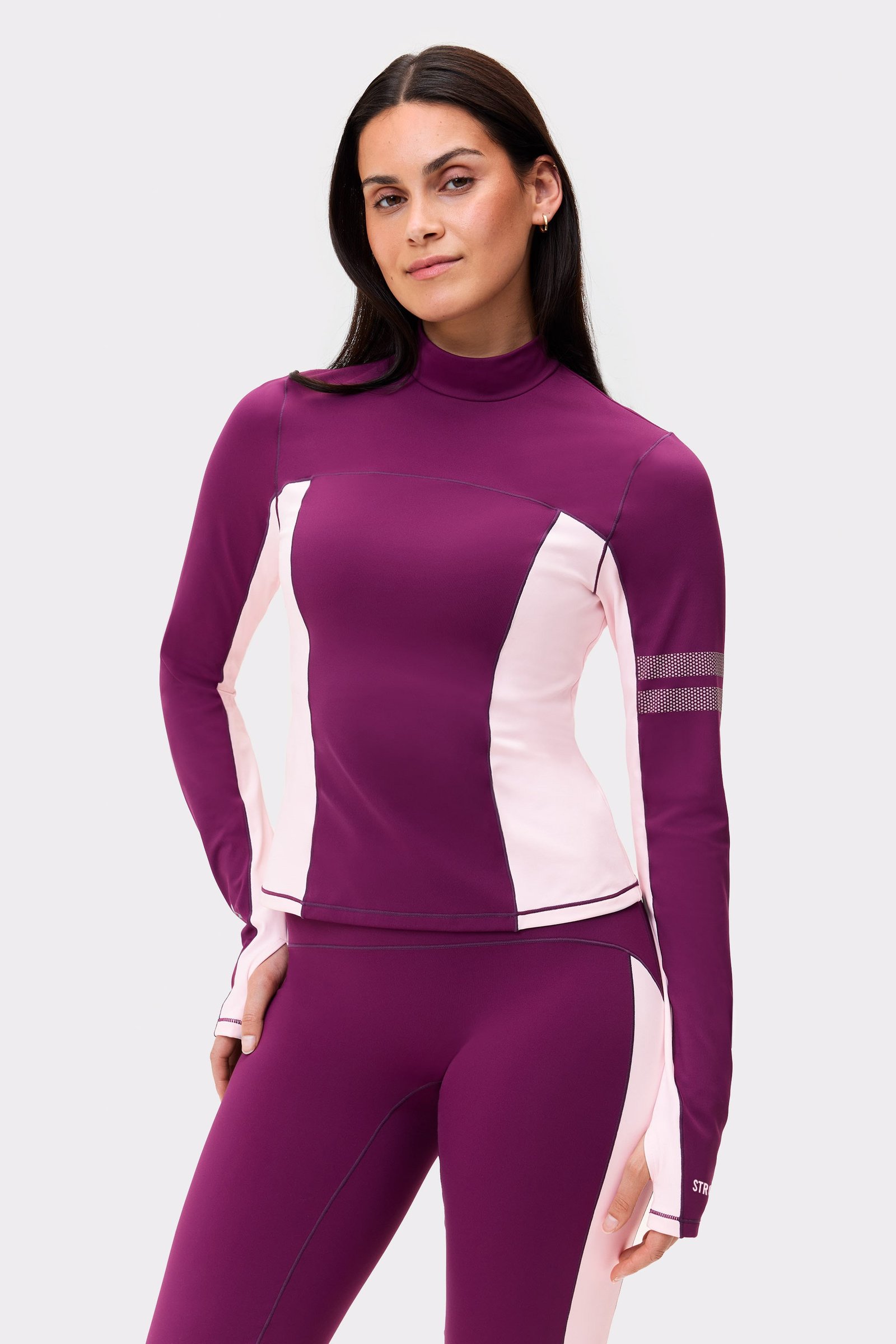 Model wearing the Stronger Thermal Poloshirt in aubergine purple and light pink with reflective sleeve details.