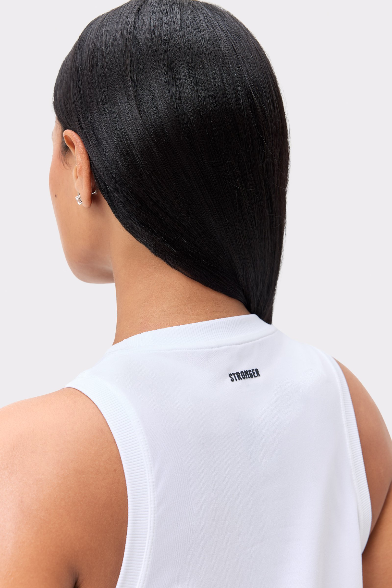 Close-up back view of the white Stronger Relaxed Tank, showing the centered logo and ribbed neckline.