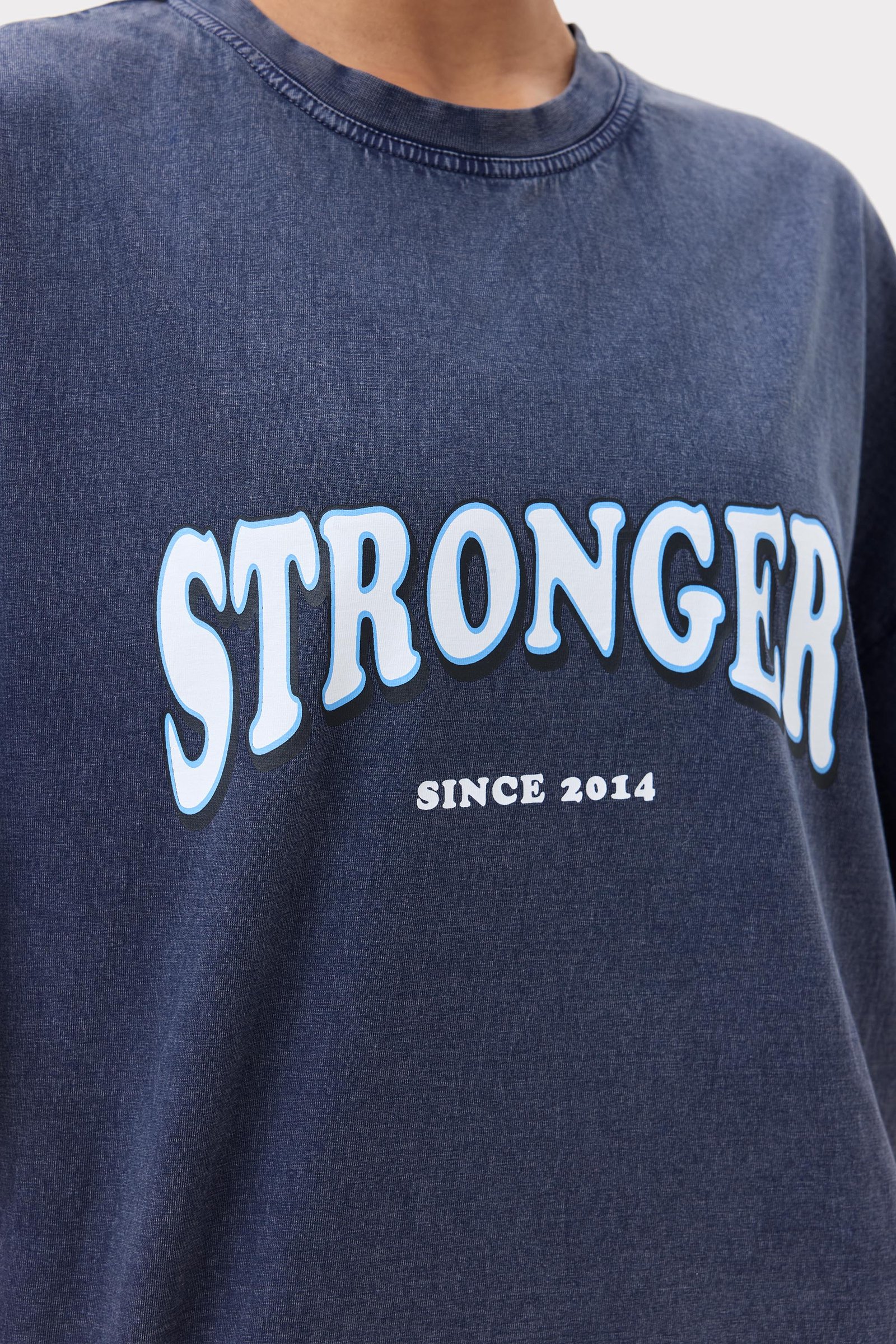 Close-up van het Oversized Crew T-shirt in gewassen marineblauw van biologisch katoen met Stronger-logo en Since 2014.