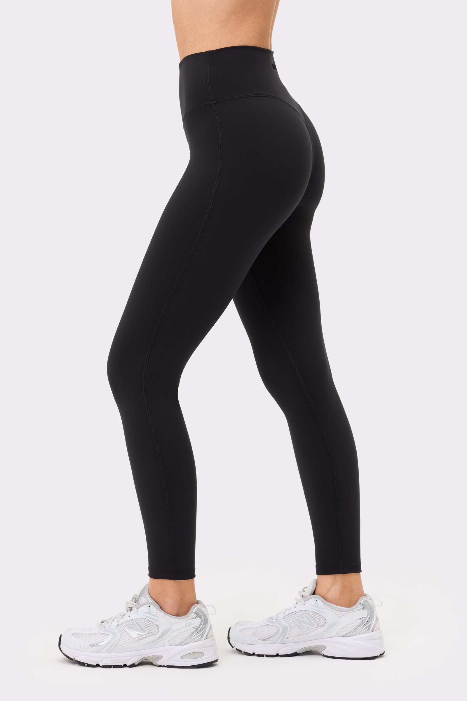 Close-up side view of a model wearing the black Soft Leggings from Stronger, highlighting their form-fitting design.