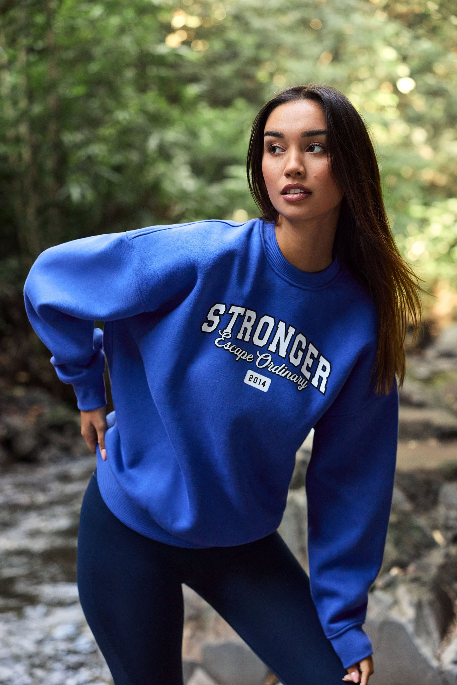 Model trägt das blaue Comfy Sweatshirt von Stronger mit Oversized-Passfall und Grafikprint auf der Vorderseite.