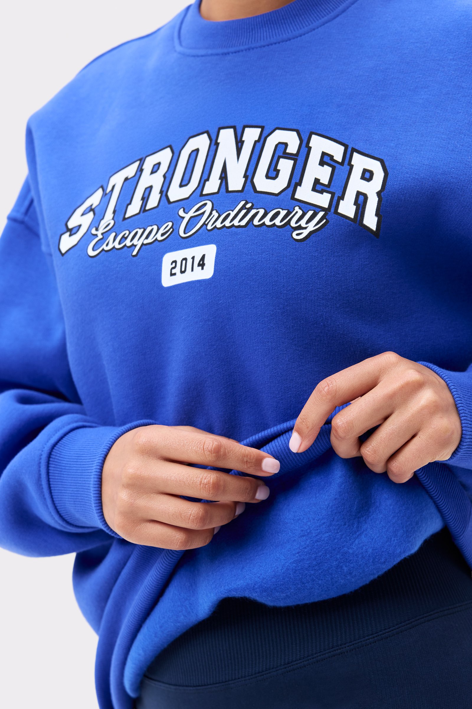 Nahaufnahme des blauen Comfy Sweatshirt von Stronger mit dem Vorderseiten-Logo und weich gebürsteter Innenseite.
