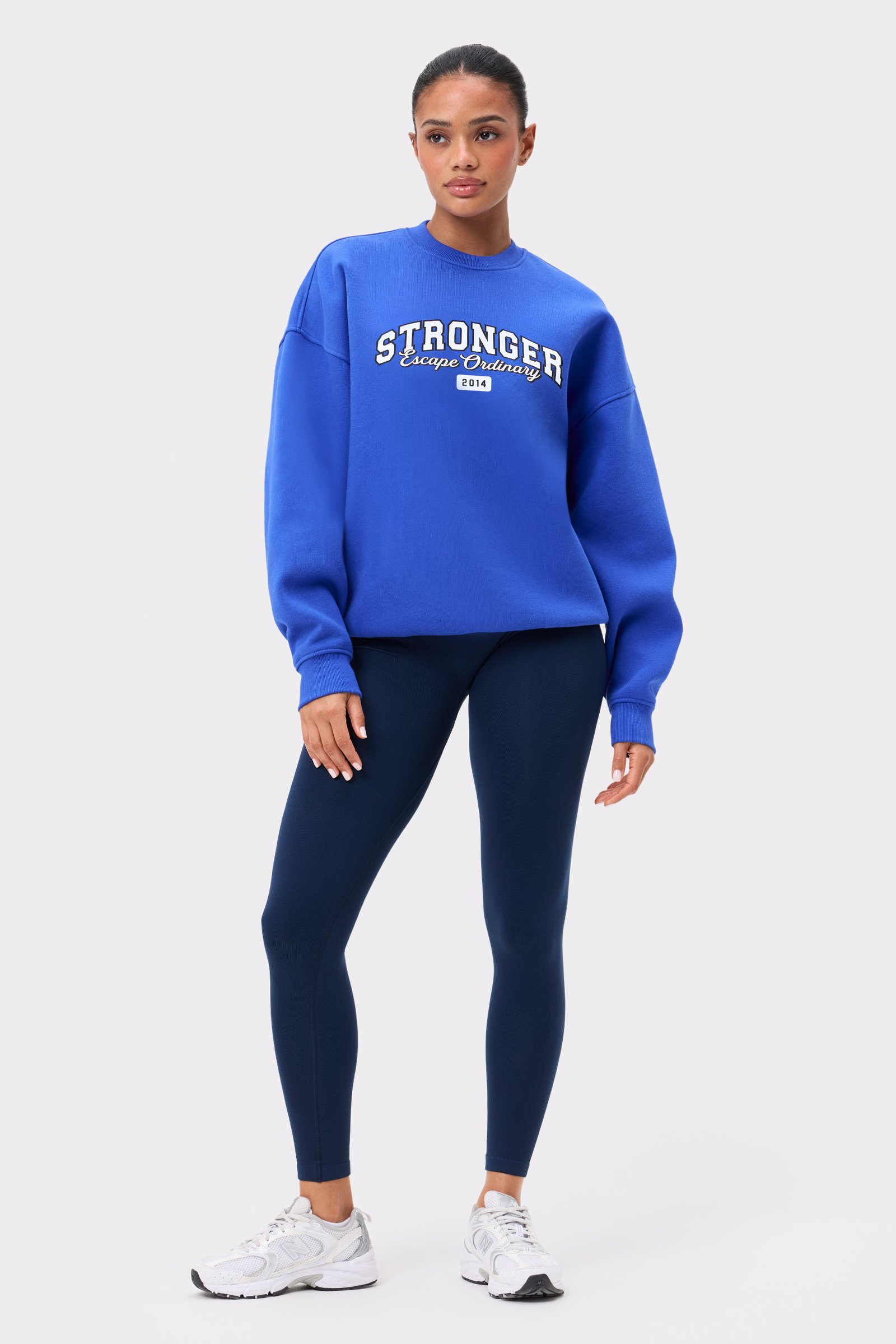 Model trägt das blaue Stronger Comfy Sweatshirt von Stronger mit Oversized-Passfall und Frontgrafik.