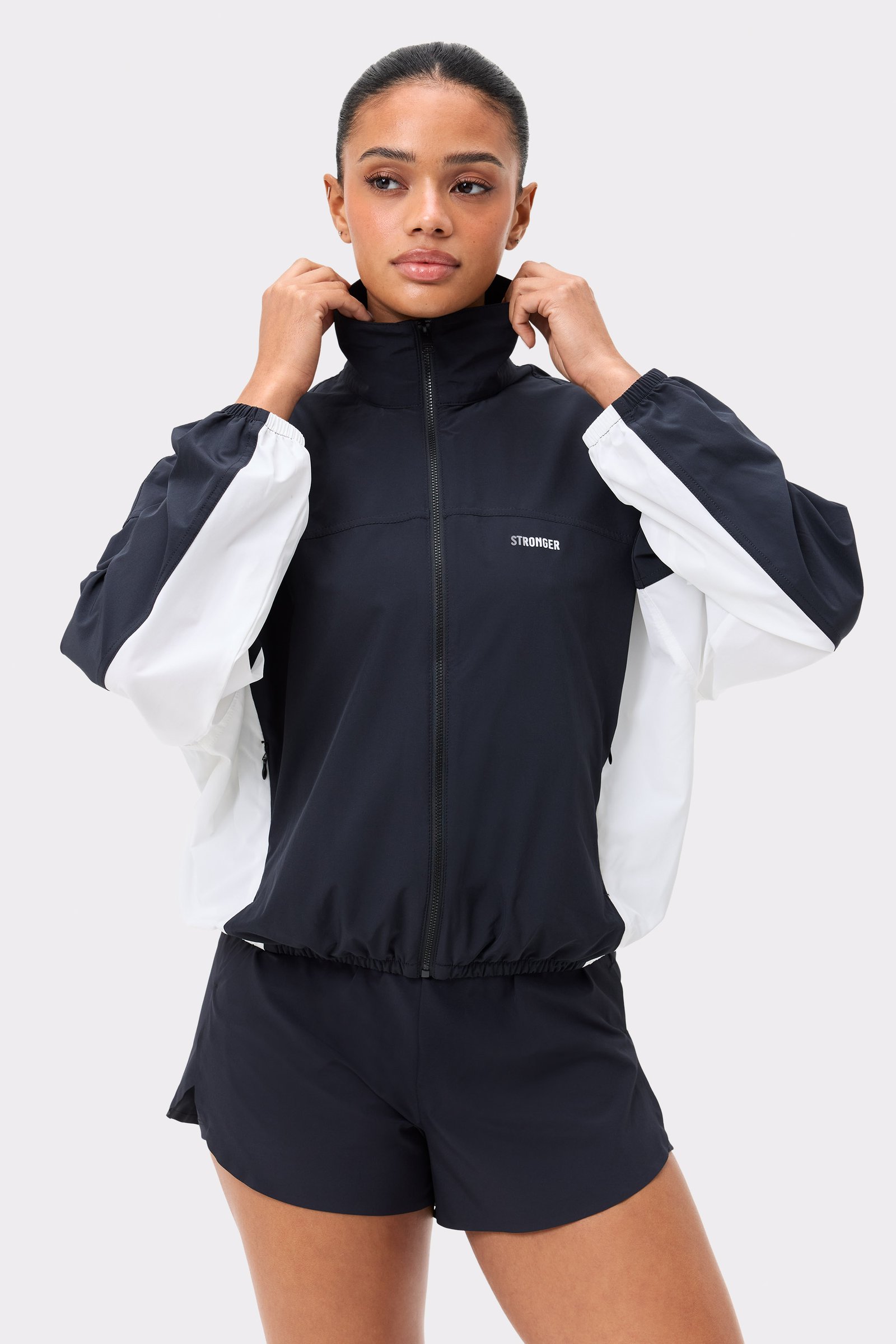 Front view of Stronger's black and white Breezy Woven Jacket, featuring a zip-up front and breathable woven fabric.