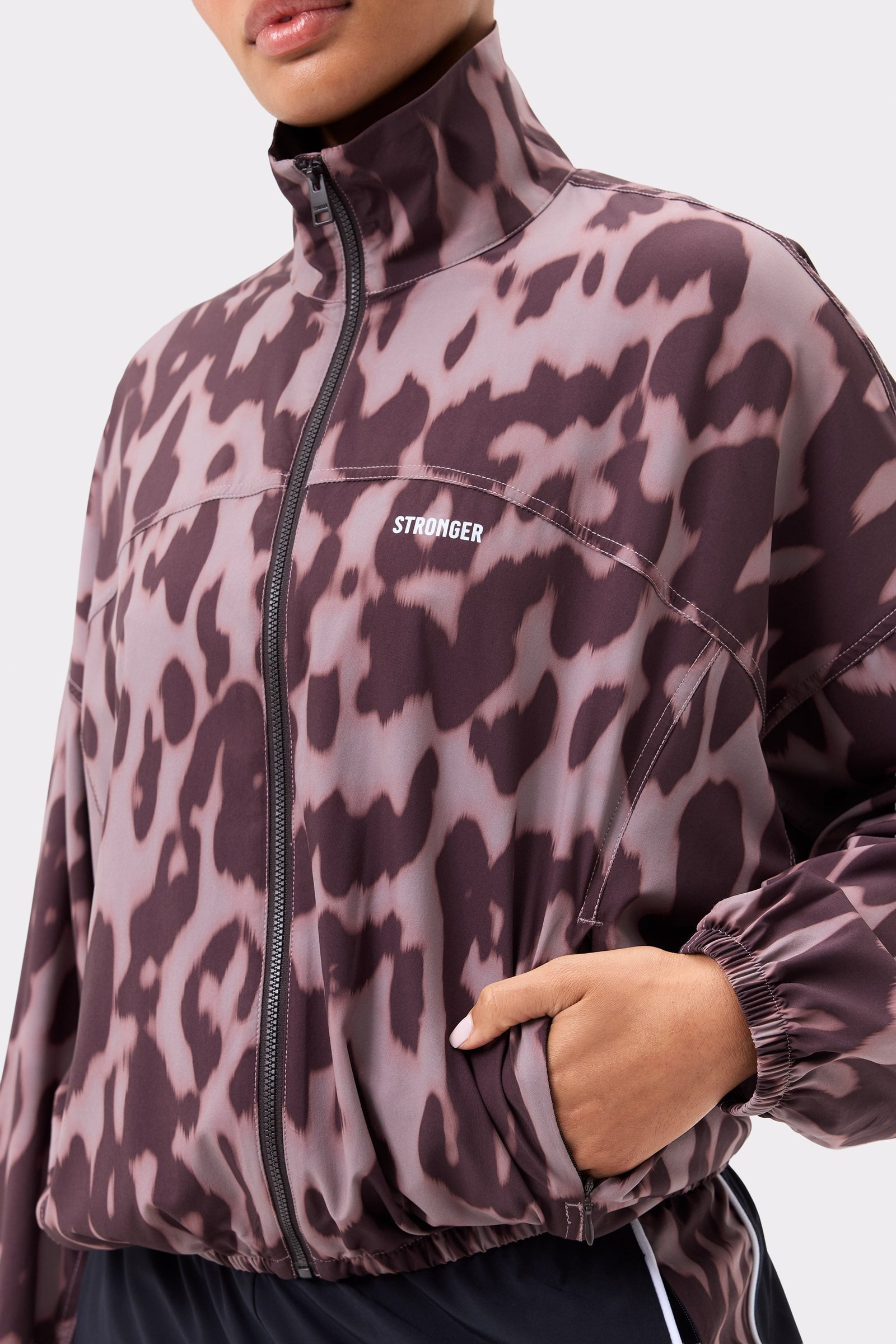 Close-up van de Stronger Breezy Woven Jacket in Leo Rush print, met een ritssluiting en stof met luipaardprint.