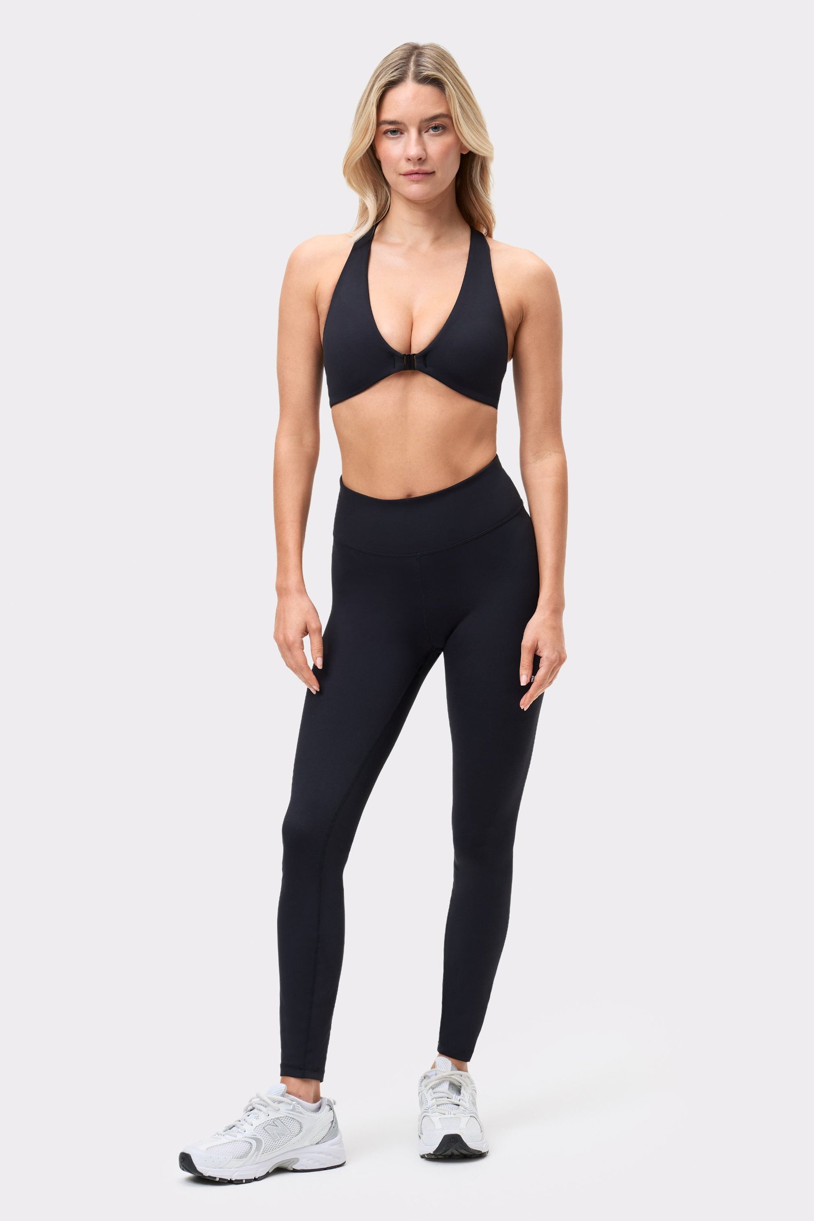 Model draagt de zwarte Front Closure Sports Bra van Stronger met bijpassende legging als complete workoutset.