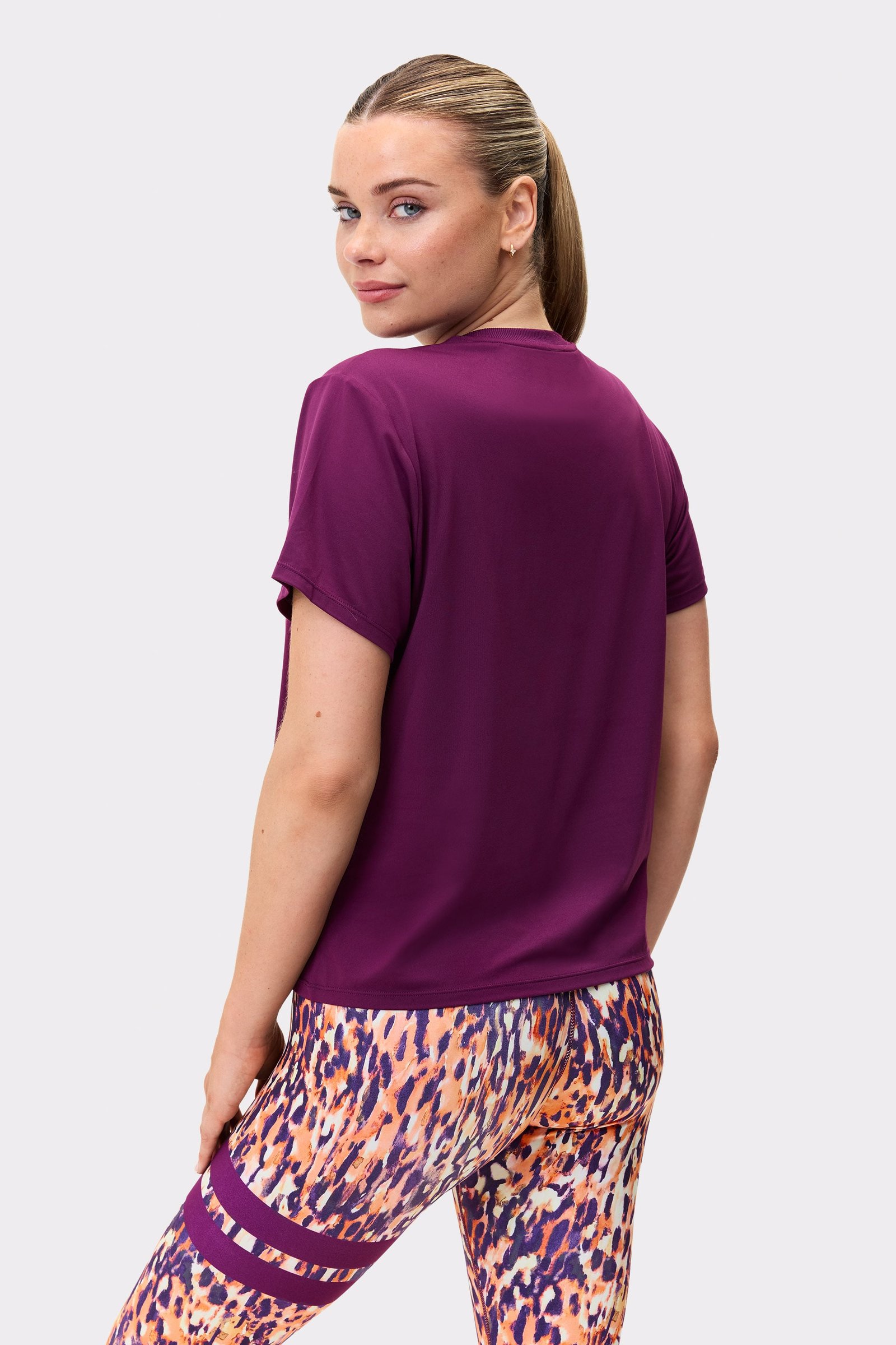 Back view of a model wearing the Relaxed Tee in aubergine purple from stronger, showing short sleeves.