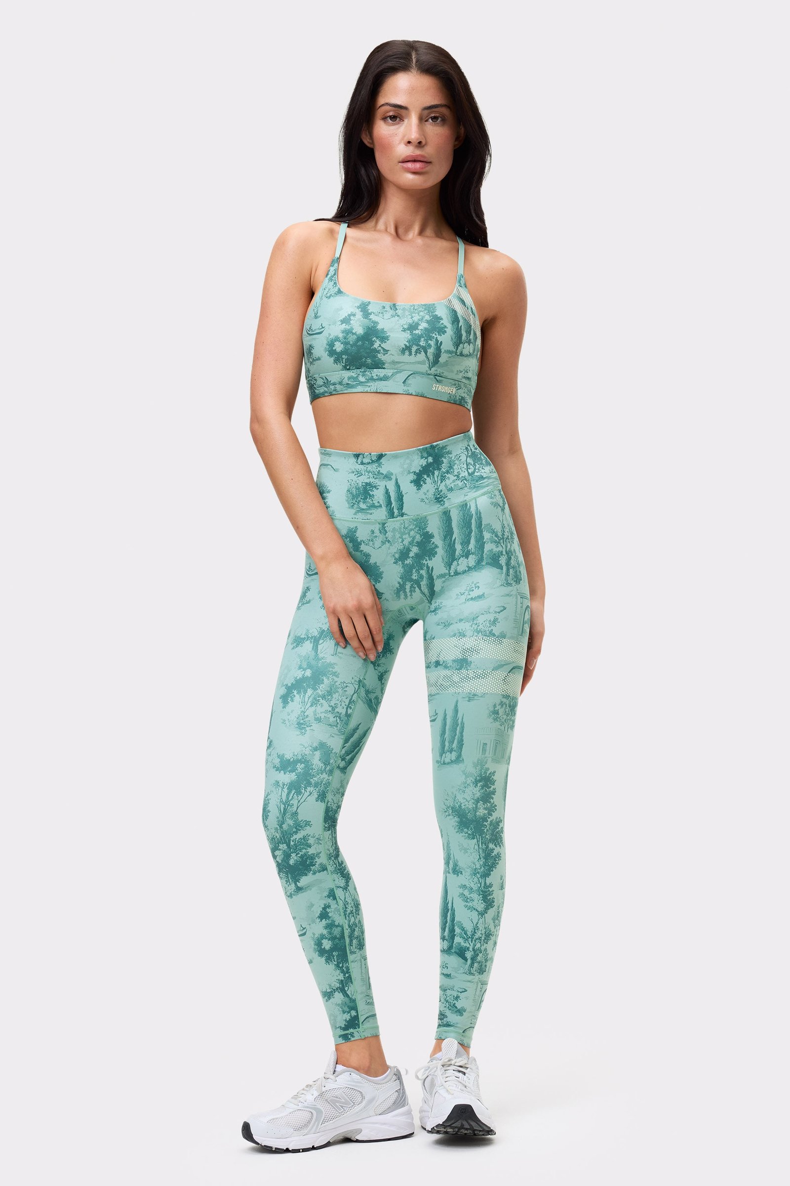 Vorderansicht eines Models im Signature Printed Strap Sports Bra und passenden Leggings mit hellblauem Toile di Roma-Print.