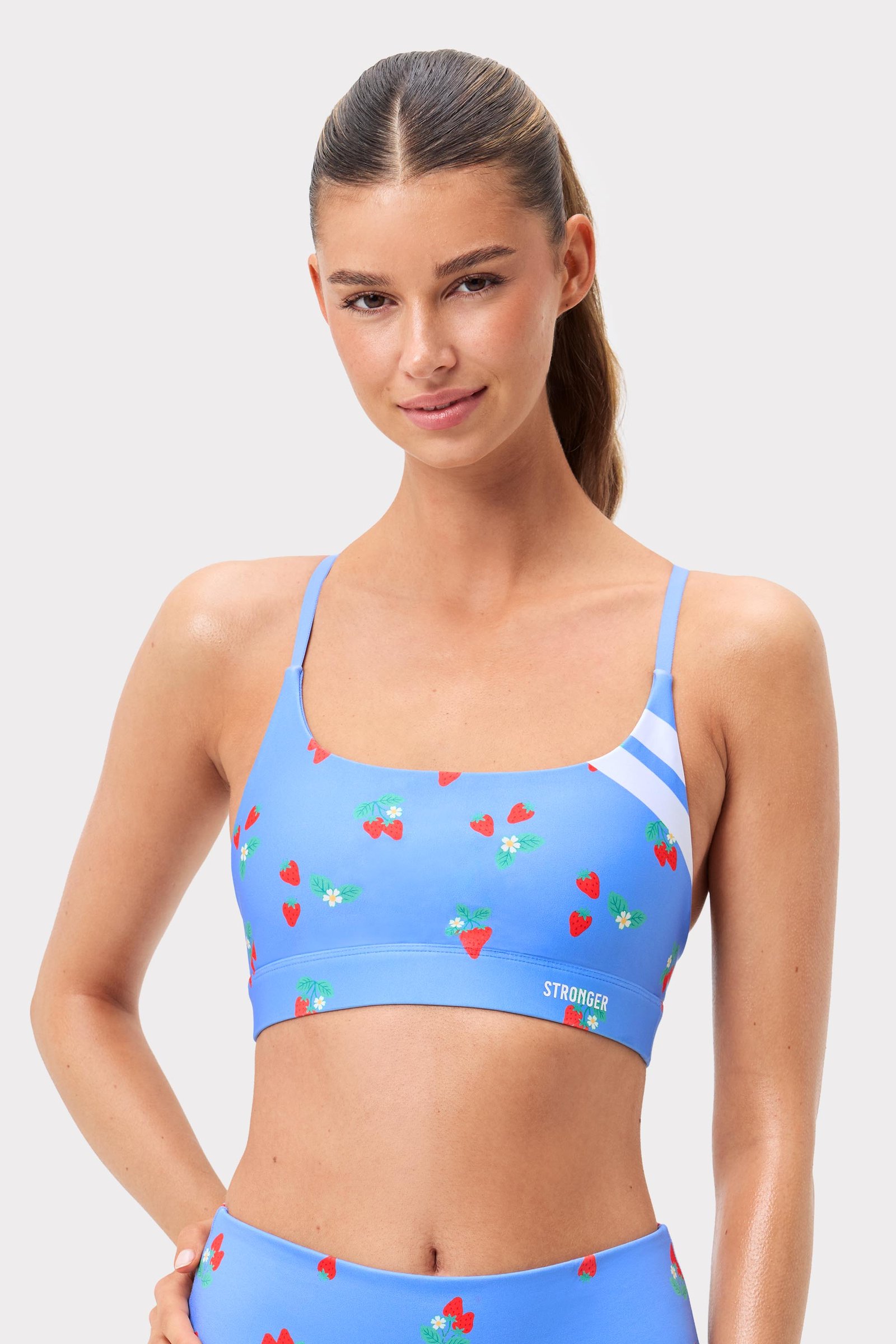 Model in de lichtblauwe Strawberry Fields Blue Signature Printed Strap Sports Bra van Stronger met witte strepen.