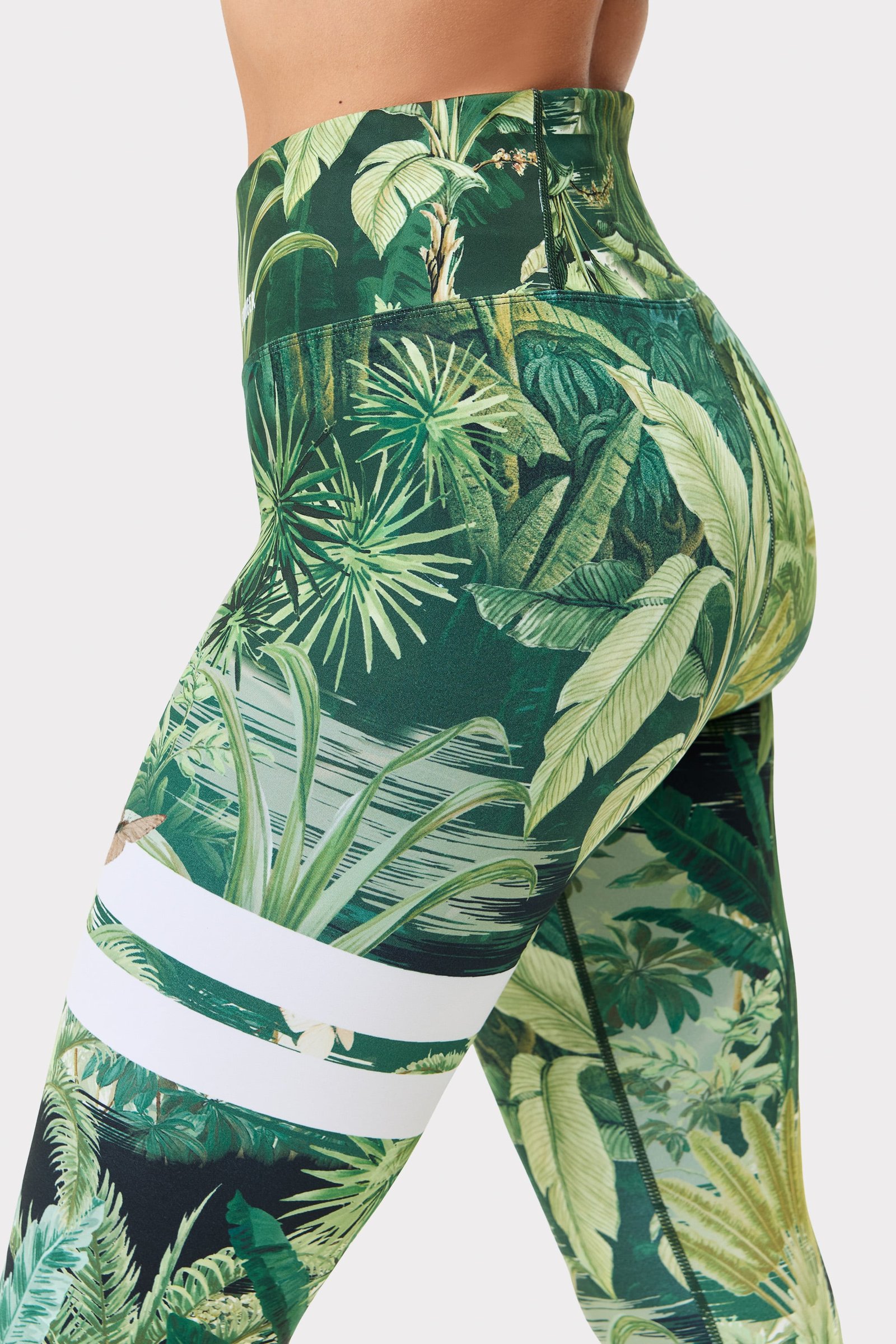 Seitenansicht der Stronger Explore Printed Leggings im Tropical Leaves-Print mit hohem Bund und charakteristischen Streifen.