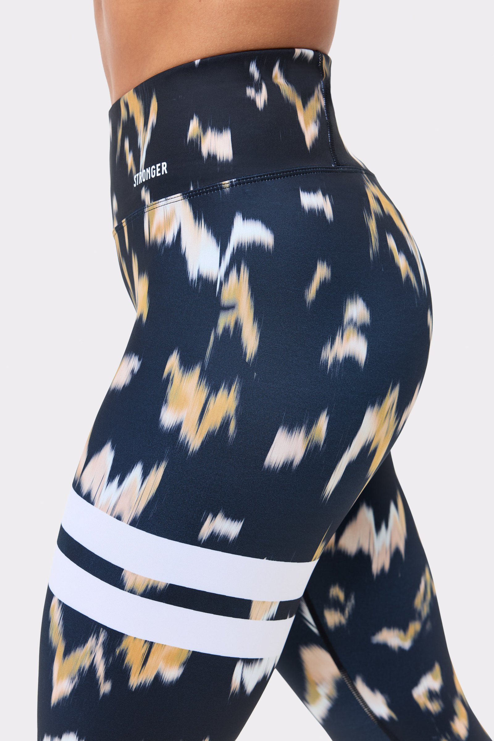 Side view of Stronger Explore Printed Leggings in Savannah Print, showcasing the abstract pattern and signature stripes.