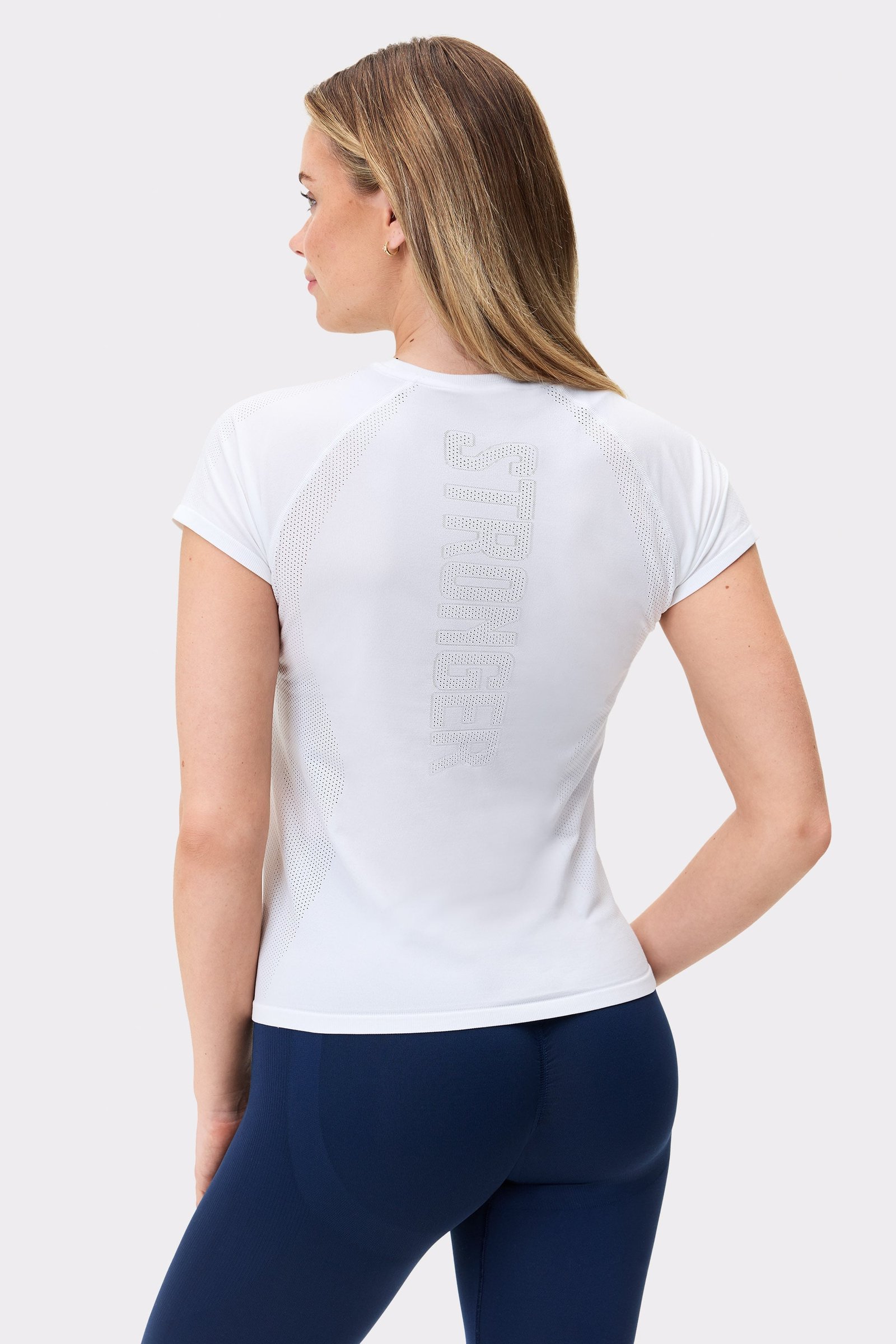 Back view of Stronger's white Seamless Performance T-shirt, featuring a vertical logo and breathable mesh panels.