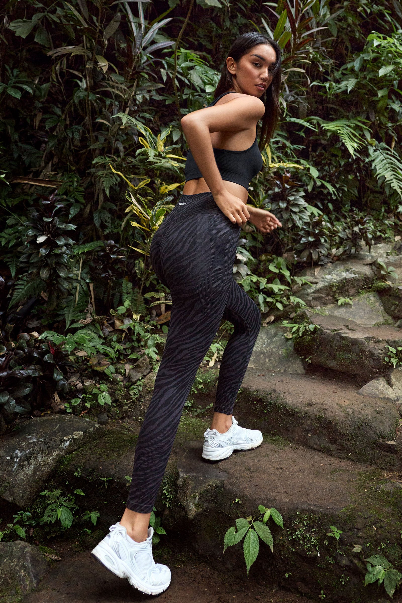 Model in Stronger Seamless Contour Jacquard Leggings mit Black Zebra-Print beim Gehen auf Steinstufen im Freien.