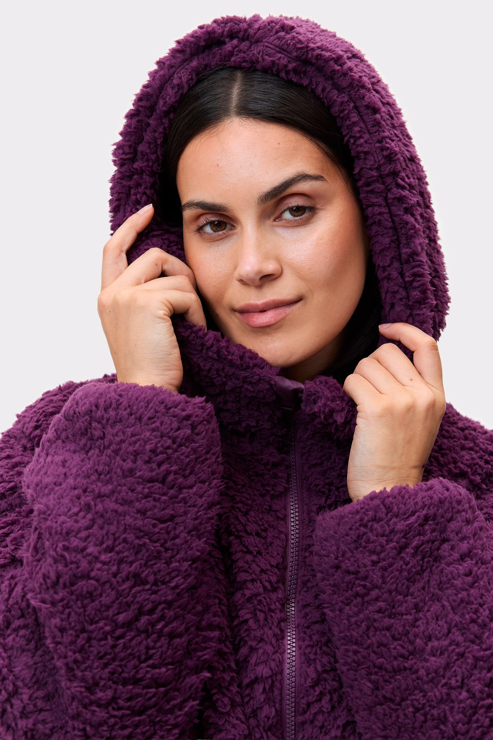 Close-up of a model wearing the dark purple Hooded Pile Jacket from stronger, showing the soft textured fabric and cozy hood.