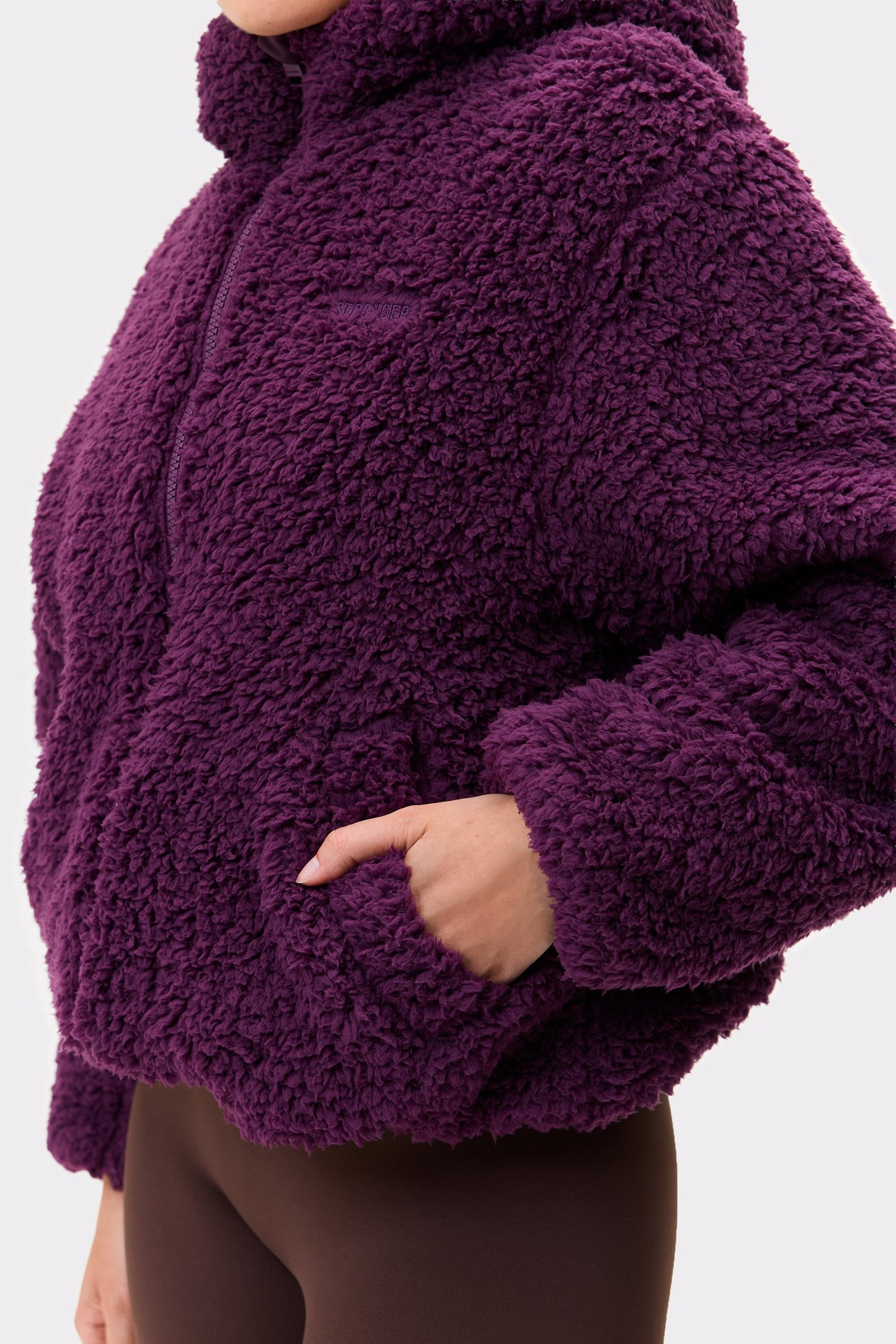 Close-up of the dark purple Hooded Pile Jacket from stronger, showcasing the soft fleece texture and pocket.