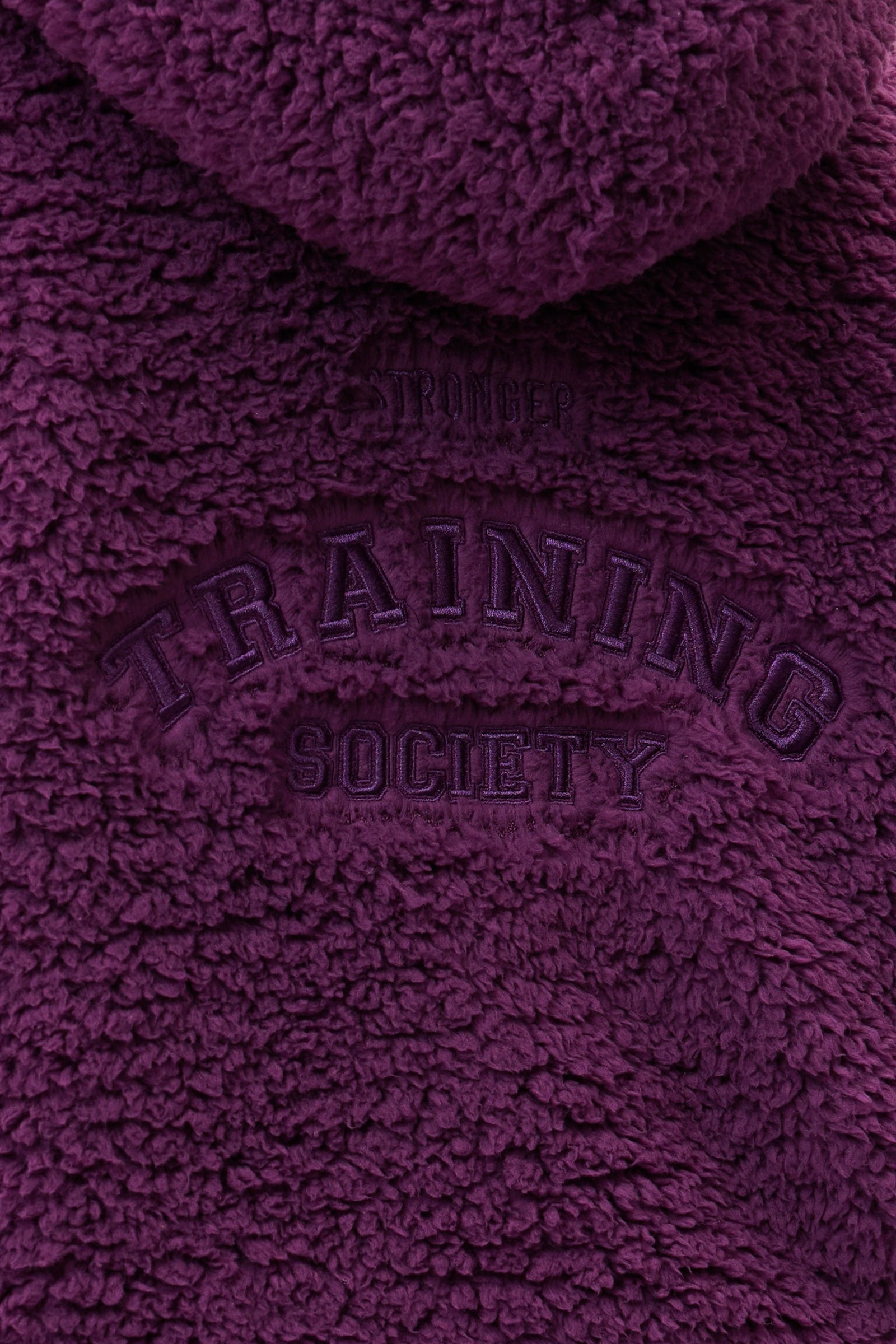 Close-up of the dark purple Hooded Pile Jacket by stronger, showing the embroidered back graphic details.