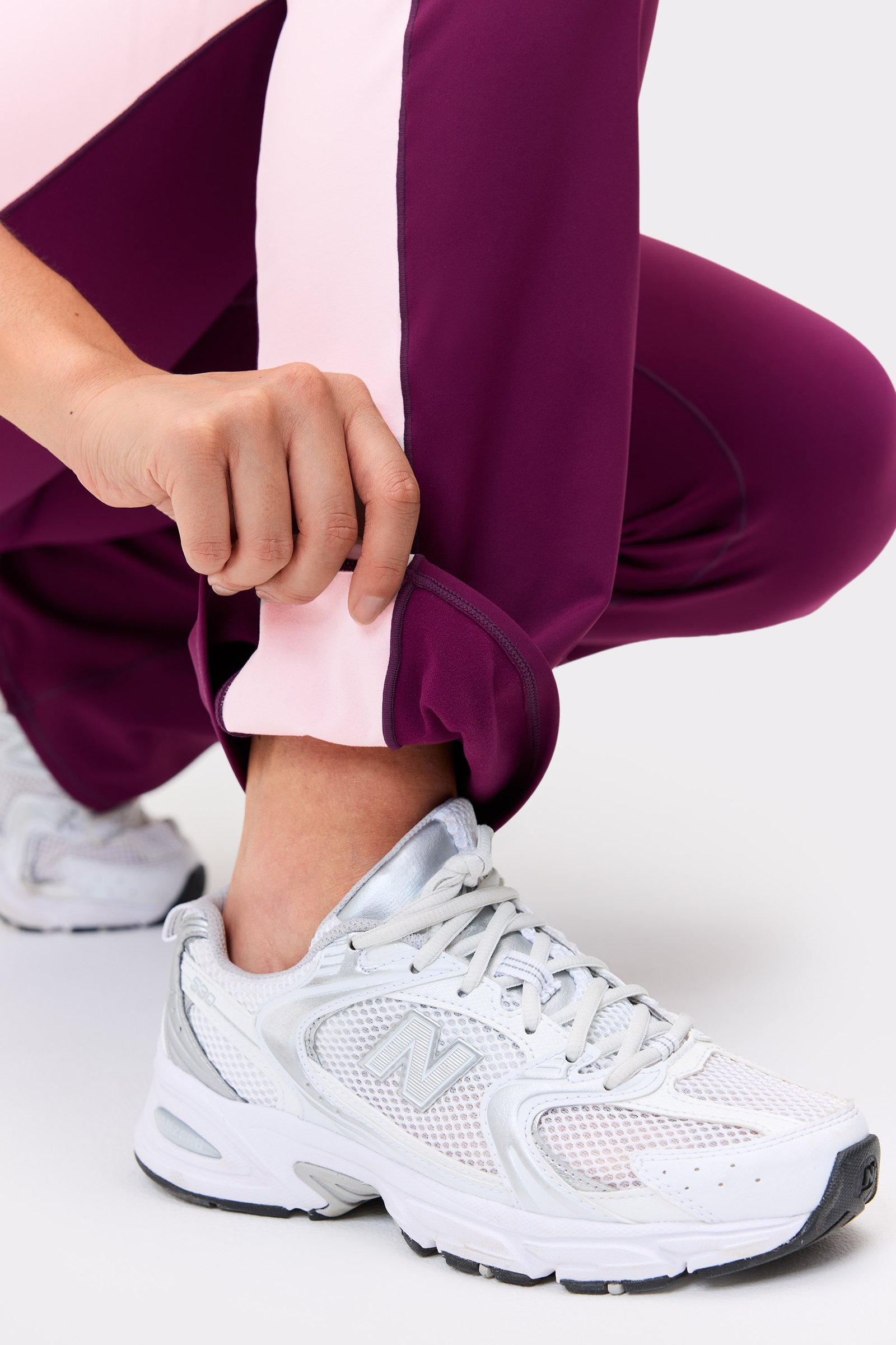 Close-up of the hem of the purple Thermal Bootcut Pants from stronger, highlighting the contrast side panel and flared leg.