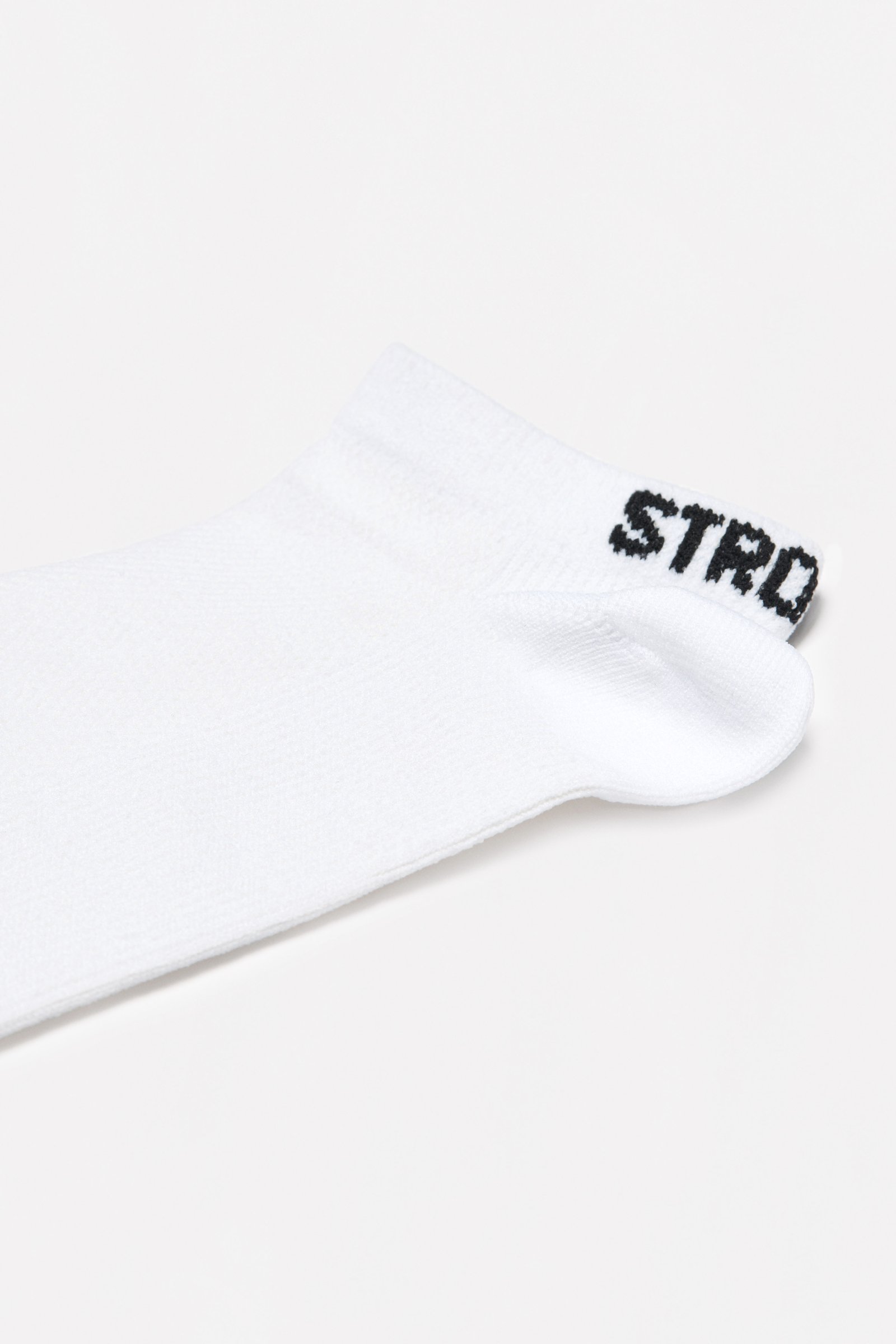 Close-up of the white Sporty Socks from stronger, showing the knitted ankle design and logotype at the back.