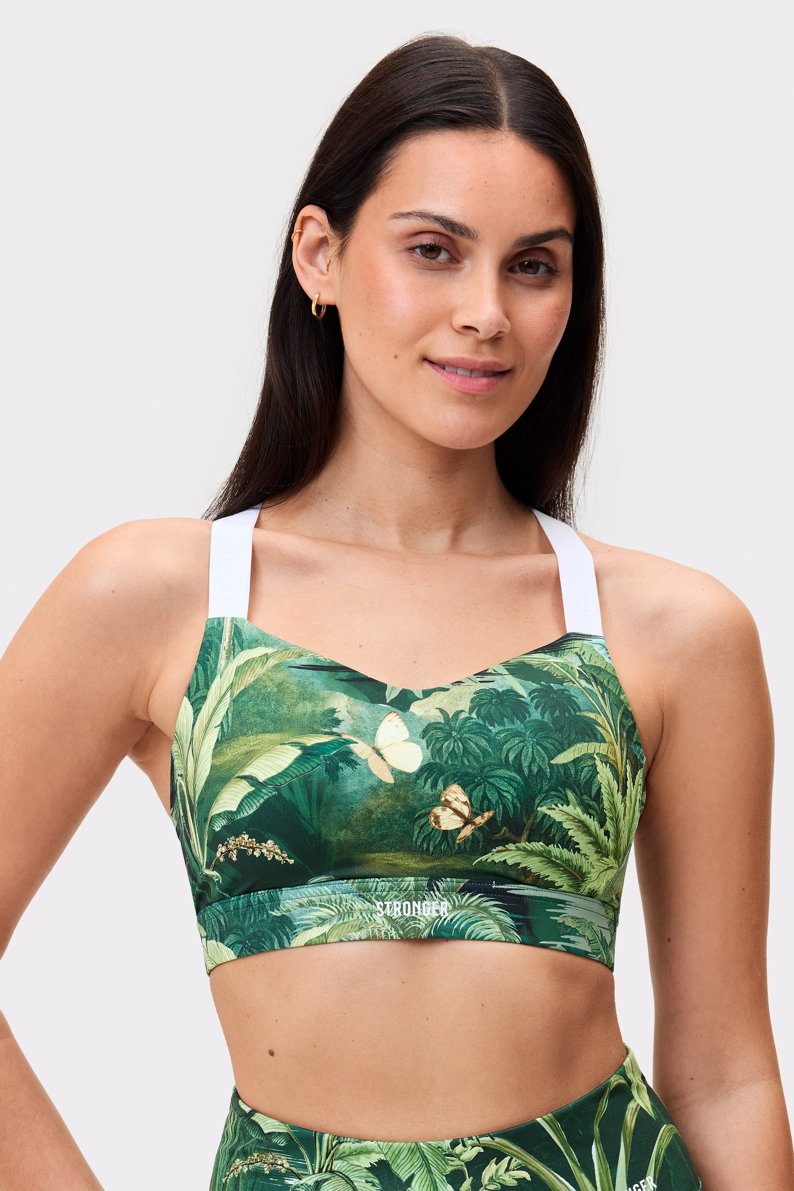 Model in Stronger Power Sports Bra mit Tropical Leaves-Print, weißen Trägern und starkem Halt für hochintensives Training.