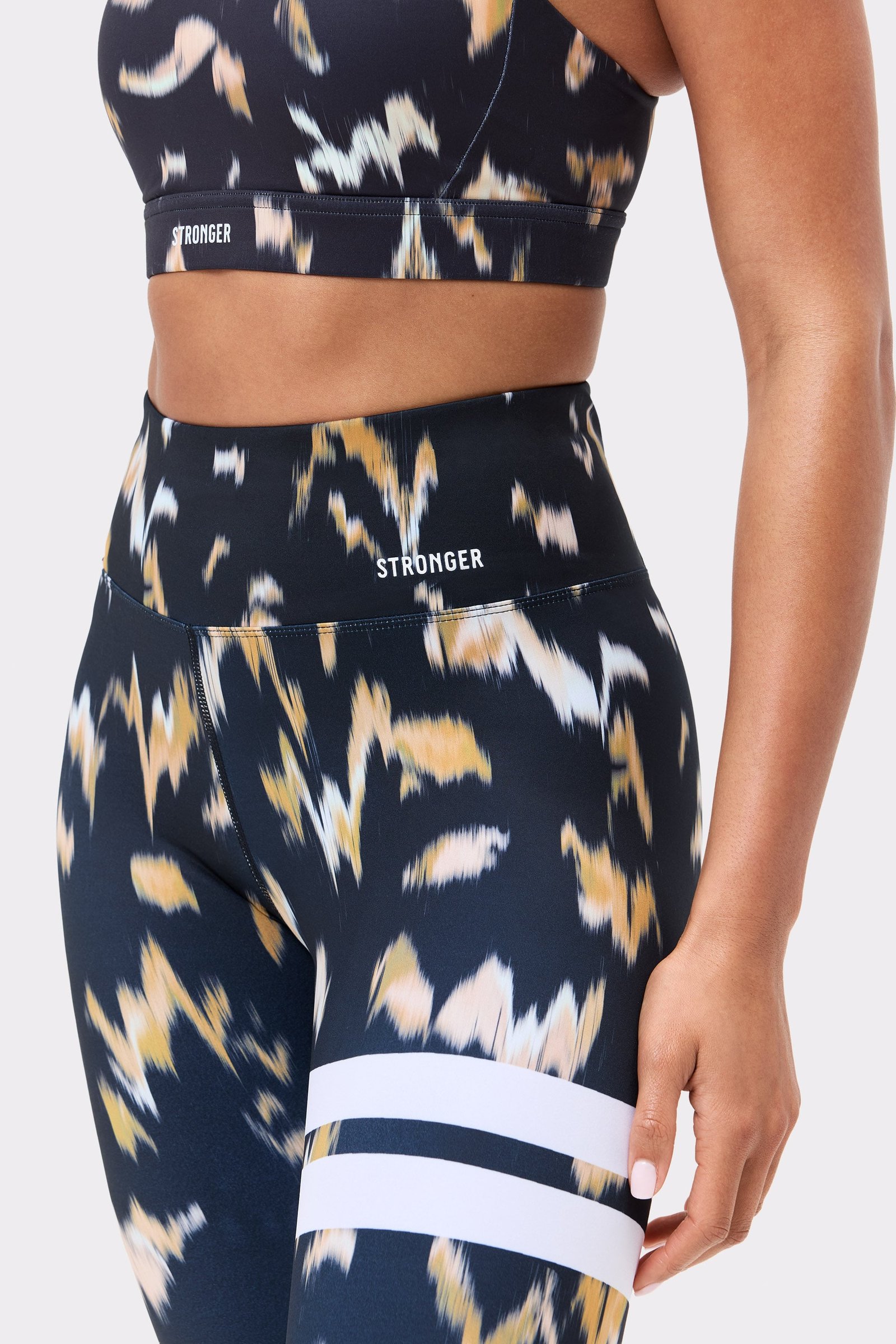 Close-up of the Savannah Print Power Sports Bra and leggings, featuring a bold abstract pattern and Stronger logo.